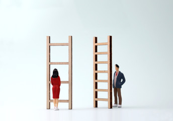 Miniature men and women standing in front of different ladders. The concept of gender...
