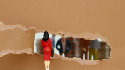 Torn paper and miniature people. The concept of gender inequality in the field of society.