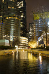 A walkway in the city of Chicago at night wet from the rain and reflecting the city lights.