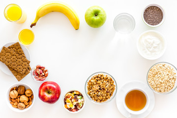 Ingredients for healthy breakfast. Fruits, oatmeal, yogurt, nuts, crispbreads, chia on white background top view copy space