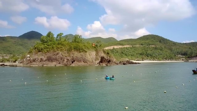 people in boats sail among buoys against excotic landscape