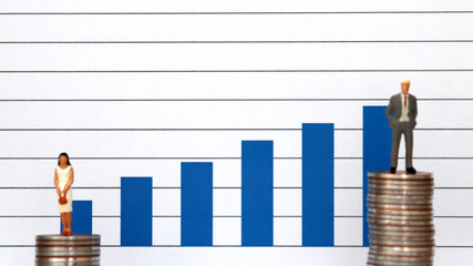 Blue bar charts and miniature people. The concept of the wage gap between men and women in...
