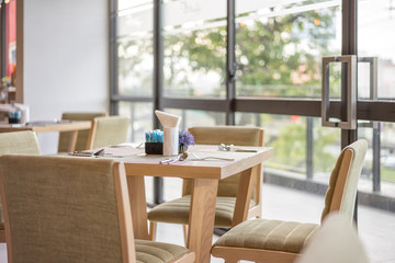Wooden table set for meal in restaurant with cozy interior, breakfast time.
