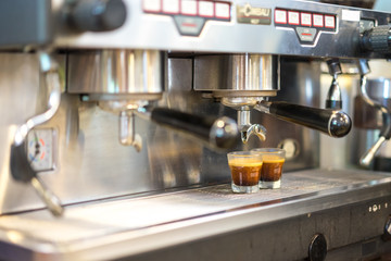 Black coffee being prepared from coffee machine into glass cup. Professional coffee brewing, hot coffee.