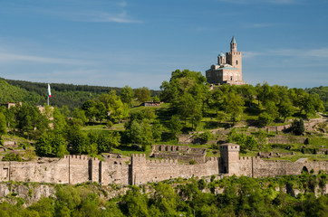Fototapeta premium Scenic view on Veliko Tarnovo, Bulgaria. Famous landmarks of the city: castle on Tsarevets hill, medieval churches, ancient stone bridge. Traditional bulgarian architecture. Sunny spring day.