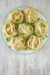 dumplings. Homemade  manti with greens in a round plate on shabby chic background . Traditional  manti with meat 