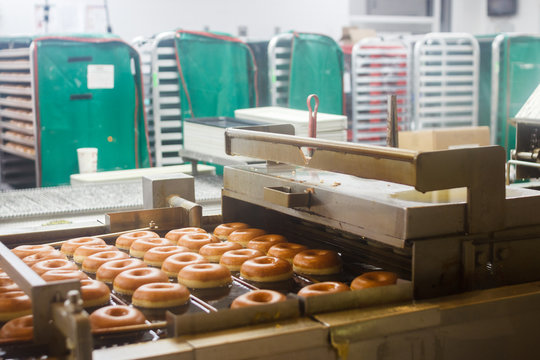 Fresh donuts leaves the conveyor. Production of donut. Doughnut