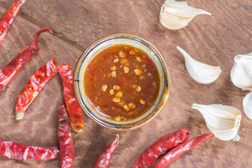 Chili sauce with garlic and dried hot chilies on wooden background, Thai food