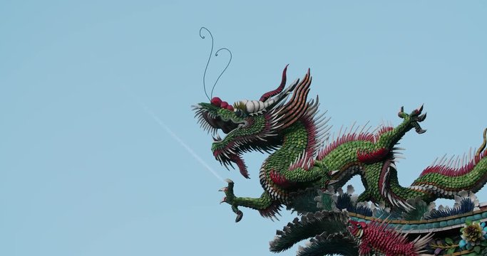 Roof decorative sculptures at Longshan Temple with the plan fly passing on the background. Taipei, Taiwan