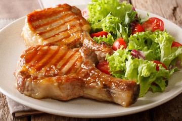 grilled chop pork honey glaze, served with a salad of fresh vegetables close-up on a plate. horizontal
