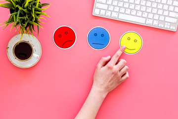 Evaluate customer service. Hand point emoji smiling, neutral, sad face on work desk on pink background top view copy space
