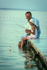 Papier Peint photo Pêcher Father with his daughter fishing in a sea on a wood pier at sunset.