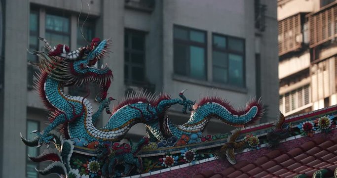 Roof decorative sculptures at Longshan Temple with a modern building on the background. Taipei, Taiwan