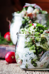 Summer cold soup with vegetables, herbs and yogurt in glass jars, rustic style, vintage wooden background