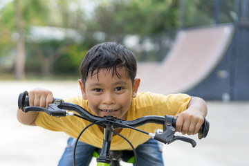asian boy riding bicycle in public park