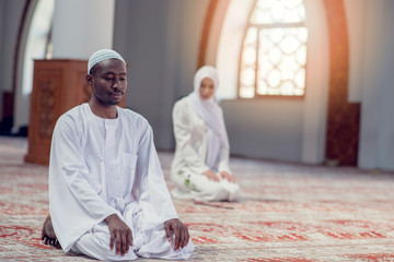 Black Muslim man and woman praying in mosque - Powered by Adobe