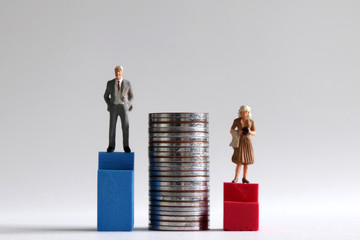 A miniature man standing on the high blue stairs on either side of a pile of coins and a miniature...