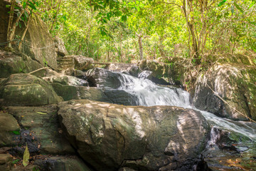 Naklejka na ściany i meble Waterfall and clear stream in the green forest