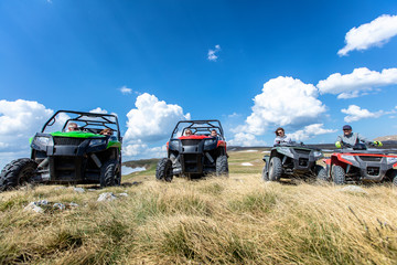 Friends driving off-road with quad bike or ATV and UTV vehicles