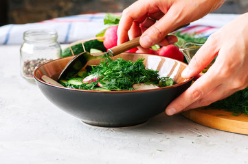 Healthy salad from fresh vegetables in making. Woman's hands mixing salad in a bowl. Cooking step by step concept.