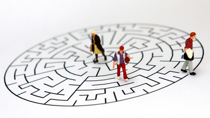 Miniature three people standing on a maze of white backgrounds.