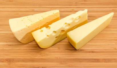 Three pieces of different cheese on the bamboo cutting board