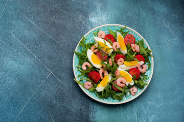 Arugula, cucumber, tomato, eggs and shrimp salad with soy sauce on ceramic plate. Selective focus. Top view.
