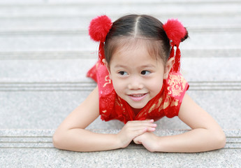 Happy little Asian child girl wearing red cheongsam with greeting gesture celebration for Chinese New Year.