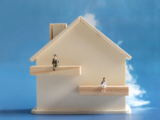 A miniature man and a miniature woman with a miniature wooden house. The concept of gender roles...