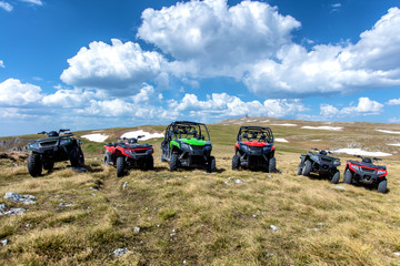 Parked ATV and UTV, buggies on mountain peak with clouds and blue sky in background © FS-Stock