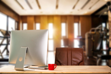 Computer Monitor, Keyboard,coffee cup and Mouse with Blank or White Screen Isolated is on the work table at the fitness gym in morning light