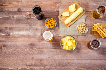 glasses of light and dark beer with assorted snacks on a wooden table background with copy space for text. bachelor party, pub, bar or degustation concept. top view, flat lay