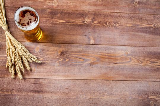 glass of beer with wheat on a wooden table background with copy space for text. flat lay, top view