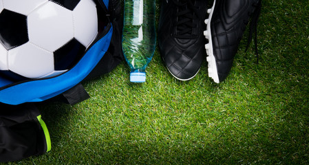 soccer ball, in a sports bag, a bottle of water and black boots, against the background of grass