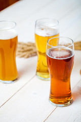 glasses of assorted beer with wheat on a wooden table background for tasting