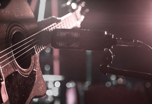 The Studio microphone records an acoustic guitar close-up. Beautiful blurred background of colored lanterns.