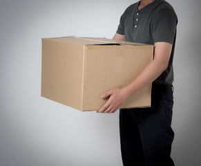Delivery man holding cardboard box on gray background