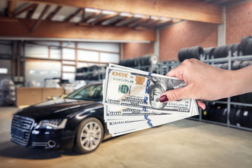 Macro on female hand with dollars and car behind