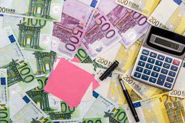 Calculator, pen and memos on euro banknotes background