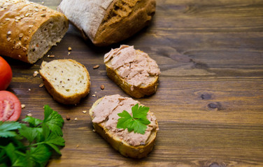 bread and sandwiches with pate and tomatoes on wooden background 
