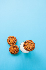 Whole wheat cookies  and glass of milk on a blue background. Top view and copy space.