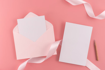 A wedding mock up concept. Wedding Invitation, envelopes, cards Papers on pink background with ribbon and decoration. Top view, flat lay, copy space