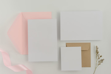 A wedding mock up concept. Wedding Invitation, envelopes, cards Papers on white background with ribbon and decoration. Top view, flat lay, copy space