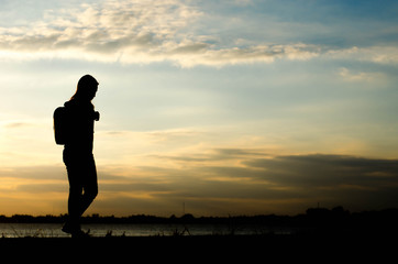 Silhouette of a woman wolking alone at the field during beautiful sunset.