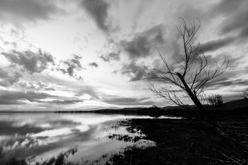 Lake shore at sunset, with perfect reflections of some clouds on