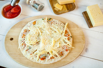 closeup raw fresh homemade traditional italian cheese pizza ready to cook on wooden cooking table with ingredients. wallpaper for pizzeria and food concept