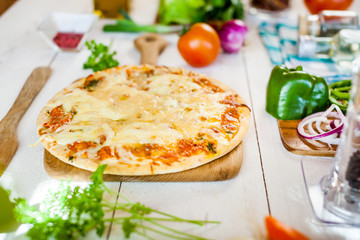 closeup fresh homemade traditional cheese italian pizza on wooden table with ingredients around. wallpaper for pizzeria and cooking food concept
