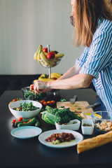 Two women cutting fresh vegetables for green veggie salad, healthy food cooking