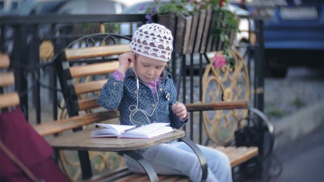 Little stylish beautiful gerl, on city streets listening to music in l headphones.