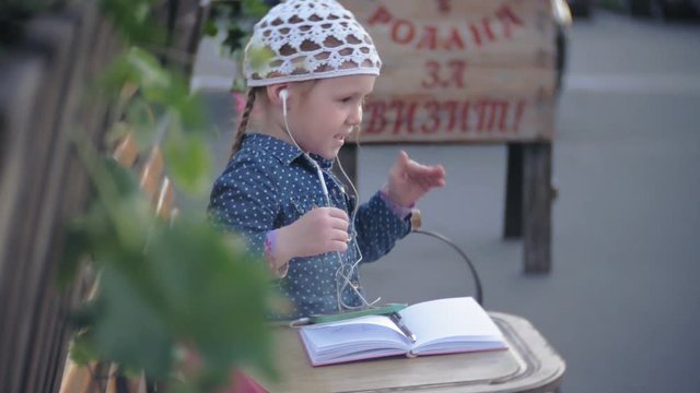 Little stylish beautiful gerl, on city streets listening to music in l headphones.